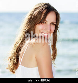 Giovane donna felice vicino al mare. Piuttosto un Sorriso ragazza con i denti sani dopo una divertente giornata sulle vacanze estive Foto Stock