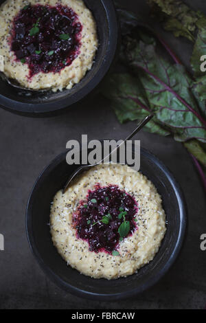 Due ciotole di miglio di polenta condito con barbabietole rosse, chia semi e foglie microgreen. Foto Stock