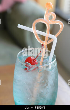 Close up e soft focus di blu oceano, Curacao rosso con ciliegie al maraschino sulla parte superiore, forma di cuore agitazione, focalizzata sul rosso cherr Foto Stock