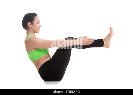 Sportivo sorridente ragazza bella le pratiche yoga, seduti in barca pongono, Navasana, rafforza l'addome, anca flessori, colonna vertebrale, campana di Piana Foto Stock