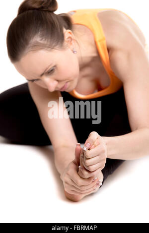 Atleta giovane ragazza in sportswear toccando il piede dolorante, infortunato dopo la pratica di sport, sensazione di dolore nel legamento, concentrarsi sulla gamba Foto Stock