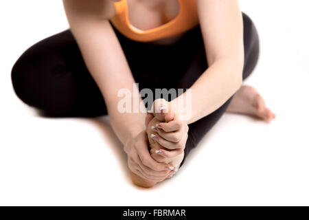 Atleta giovane ragazza in azienda di abbigliamento sportivo il mal di piedi, infortunato dopo la pratica di sport, vicino, il focus sulla gamba e bracci Foto Stock