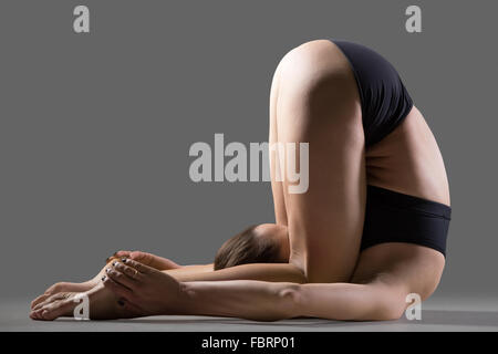 Giovane e bella montare donna in pantaloncini abbigliamento sportivo facendo sport esercizi, spalla stand, karna pidasana, ginocchio all'orecchio o Sordo Foto Stock