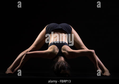 Bella giovane montare donna in abbigliamento sportivo fare sport esercizio per la flessibilità ampia zampe piegare in avanti la postura, Prasarita Foto Stock