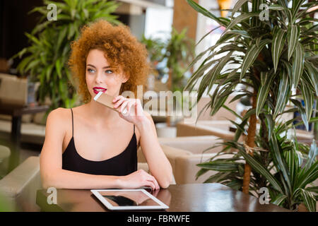 Ritratto di un pensieroso redhead donna con capelli ricci seduti nel ristorante Foto Stock