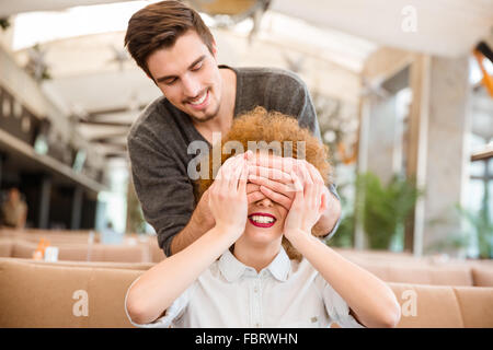 Ritratto di un uomo che copre gli occhi alla sua fidanzata nel ristorante Foto Stock