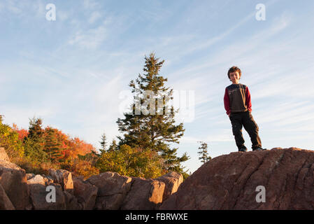 Ragazzo che sta sulla cima della roccia Foto Stock