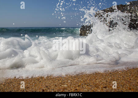 Un basso angolo di close-up di un'onda di schiantarsi sulla spiaggia Foto Stock