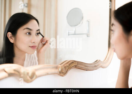 Donna che guarda in uno specchio, applicando eye shadow Foto Stock