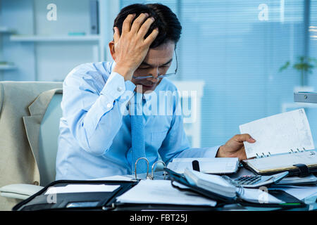 Sottolineato imprenditore con una grande quantità di lavoro Foto Stock