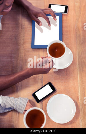 I colleghi holding tazzine di caffè mentre utilizzando le tecnologie Foto Stock