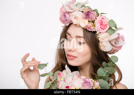 Ritratto di bellezza di gara attraente giovane femmina nella corona di rose con bouquette di fiori isolati su sfondo bianco Foto Stock
