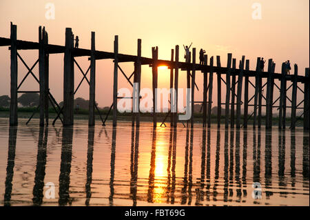 Sagome di persone che attraversano la U Bein bridge in Amarapura vicino a Mandalay al tramonto del Myanmar Foto Stock