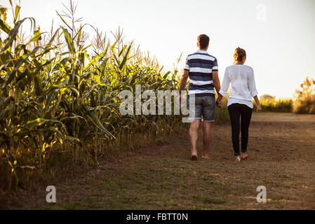 Giovane a piedi lungo la strada sterrata accanto a cornfield Foto Stock