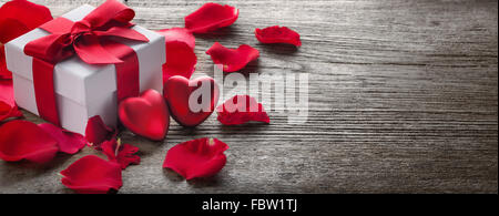 Confezione regalo e mazzo di rose rosse sul legno rustico,sfondo di San Valentino. Foto Stock