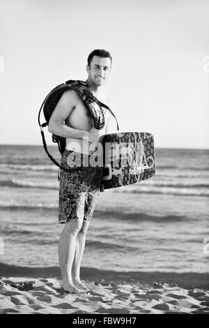 Ritratto di un giovane uomo kitsurf presso la spiaggia sul tramonto Foto Stock