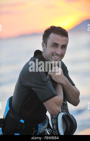 Ritratto di un giovane uomo kitsurf presso la spiaggia sul tramonto Foto Stock