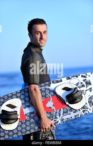 Ritratto di un giovane uomo kitsurf presso la spiaggia sul tramonto Foto Stock