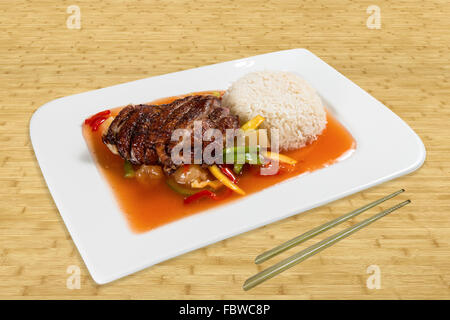 Cucina cinese su una piastra in piedi su un tavolo. Anatra arrosto con riso di verdure e salsa rossa. Legno di sfondo Foto Stock