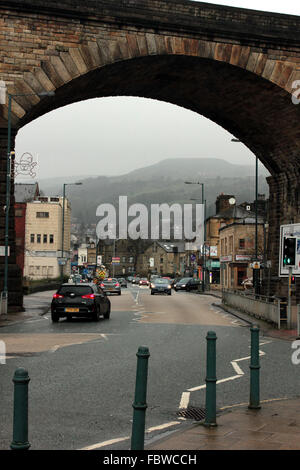 Una vista misteriosa attraverso uno degli archi del viadotto ferroviario a Todmorden, nello Yorkshire occidentale. Il viadotto di pietra domina la città. Foto Stock