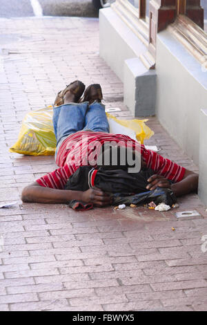 Povero mendicante che giace nella sporcizia Foto Stock