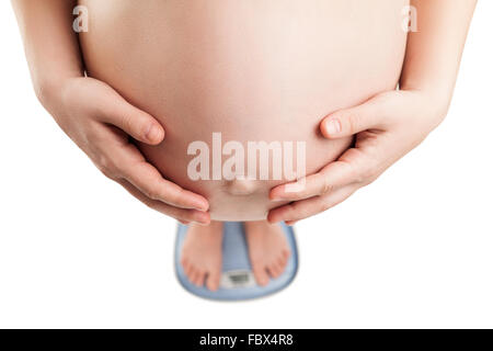 Donna incinta in piedi sul bilanciamento del peso Foto Stock