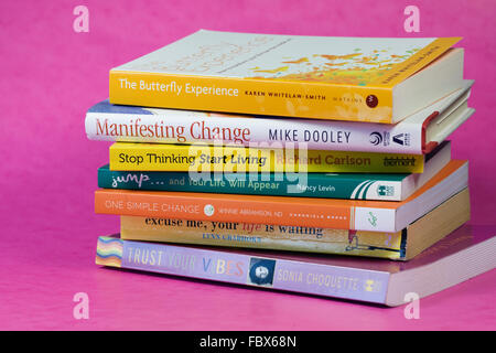 Una pila di libri di auto-aiuto su un sfondo rosa. Foto Stock