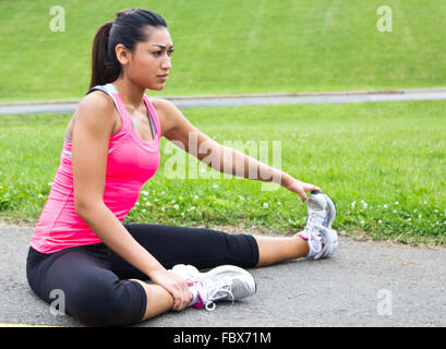 Giovane donna si estende prima di eseguire Foto Stock