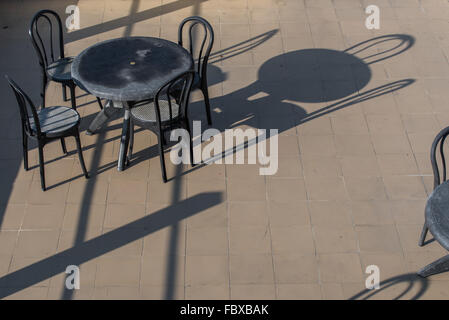 Cene Alfresco. Esterno in metallo nero tavolo e sedie di colata ombre profonde nella luce del mattino. Bomdila, India. Foto Stock