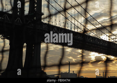 Distorta visione industriale di Manhattan Bridge waterfront sunrise New York City attraverso un recinto di filo Foto Stock