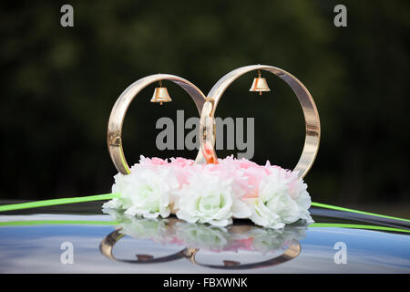 Anelli d'oro e rose fiori sulla vettura di nozze Foto Stock