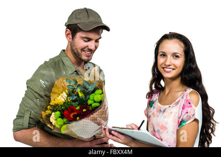 Donna firma per bouquet consegna con sorridente postino Foto Stock
