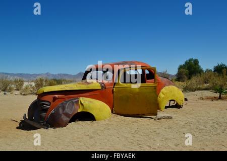 Abbandonata la formazione di ruggine e ripartiti vecchia auto in un deserto Foto Stock