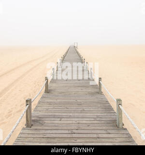 Passerella in legno su un foggy spiaggia di sabbia. Figueira da Foz, del Portogallo, dell'Europa. Foto Stock