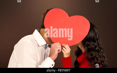 Immagine composita del giovane che copre i volti con cuore di carta Foto Stock