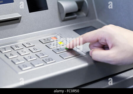 Mano umana toccando bancomat Foto Stock