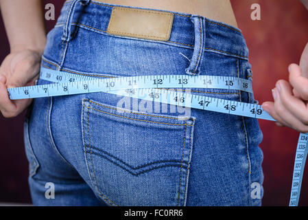 Slim donna asiatica , indossano jeans, misurando la sua forma del corpo, alla cintura, glutei Foto Stock