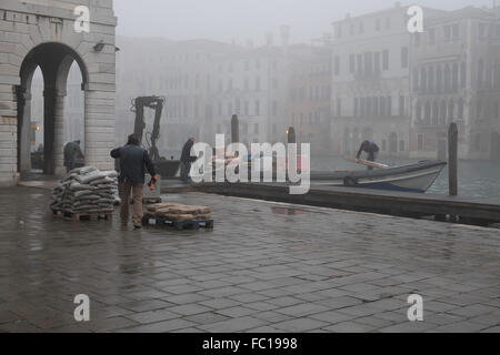 I lavoratori di scarico di merci da una barca ormeggiata sul Canal Grande a Venezia Foto Stock