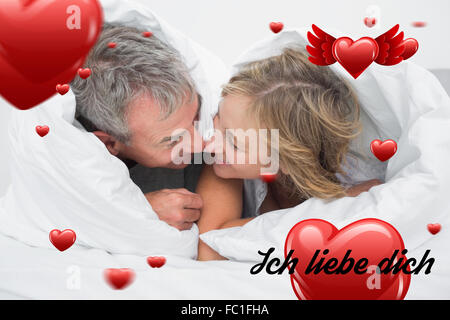 Immagine composita di amorevole coppia di mezza età sotto il piumino Foto Stock