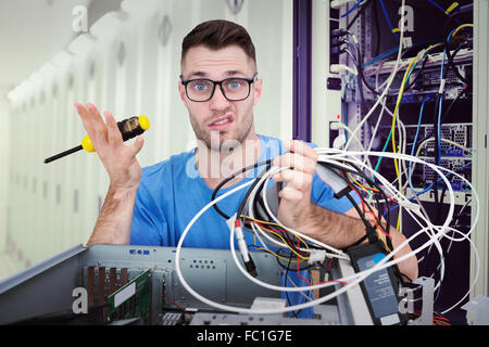 Immagine composita del ritratto di confuse it professional con cacciavite e cavi di fronte ope Foto Stock