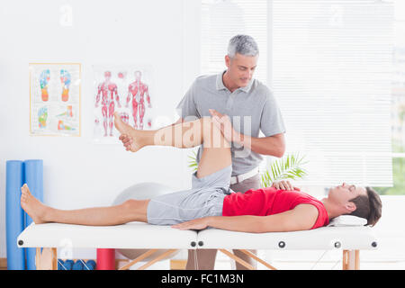 Fisioterapista facendo massaggio delle gambe al suo paziente Foto Stock