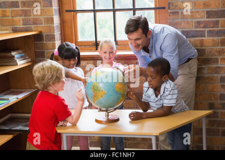 Carino gli alunni e gli insegnanti guardando il globo in biblioteca Foto Stock