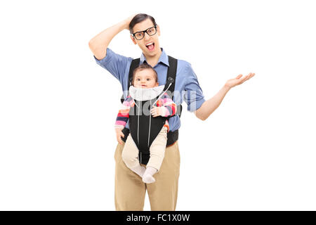 Studio shot di un giovane confuso padre portando la sua figlia e gesticolando con la sua mano isolati su sfondo bianco Foto Stock