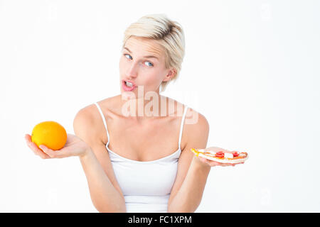 Bella donna di decidere tra la pizza e un arancio Foto Stock