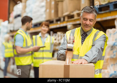 Lavoratore di magazzino la sigillatura di scatole di cartone per la spedizione Foto Stock