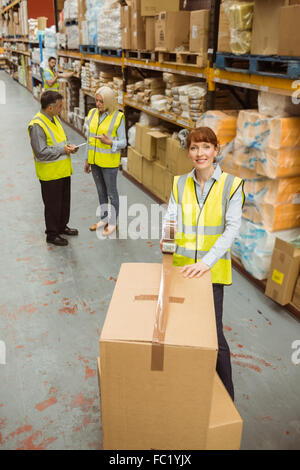 Lavoratore di magazzino la sigillatura di scatole di cartone per la spedizione Foto Stock