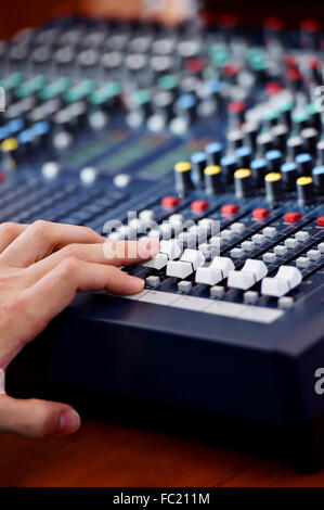 Dettaglio con una mano la regolazione dei livelli del suono su un Professional mixer audio Foto Stock