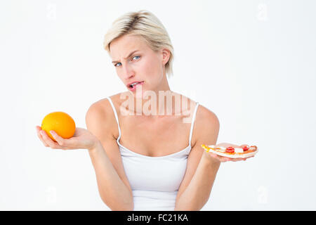 Bella donna di decidere tra la pizza e un arancio Foto Stock