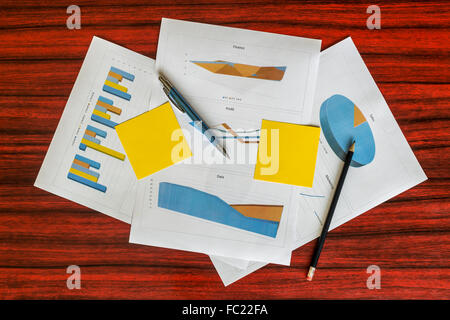 Mazzetto di stampare grafici e diagrammi con note di giallo, fermagli per carta e penna su di essi Foto Stock