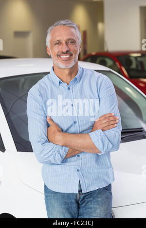 Cliente sorridente appoggiato su auto con le braccia incrociate Foto Stock
